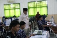PANTAU KESIAPAN SISWA: Bupati Tanjung Jabung Barat, Drs. H. Anwar Sadat, M.Ag., mengamati langsung antusiasme siswa saat mengerjakan Tes Kemampuan Akademik (TKA) 2026 berbasis komputer di salah satu SMP negeri, Kamis (09/04). Peninjauan ini dilakukan untuk memastikan standarisasi mutu pendidikan dan kelancaran infrastruktur digital di sekolah-sekolah Tanjab Barat. (FOTO :Dok. Prokopim)
