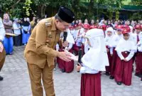 Wali Kota Jambi, Dr. dr. H. Maulana berinteraksi langsung dengan seorang siswi SD di halaman sekolah pada acara pelaksanaan "Gerakan Ayah Mengantar Anak di Hari Pertama Sekolah" (GAMAS) yang diselenggarakan di Kota Jambi. (Foto: Dok. Humas Kota Jambi)