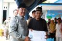 Bupati Tanjung Jabung Barat, Drs. H. Anwar Sadat, M.Ag., didampingi oleh Kepala Dinas Dukcapil, menyerahkan secara langsung bantuan dokumen kependudukan baru berupa Kartu Keluarga (KK) dan Kartu Tanda Penduduk (KTP) yang telah dicetak ulang kepada salah satu warga korban kebakaran di Kelurahan Teluk Nilau, Kecamatan Pengabuan. (FOTO : Dok. Prokopim TJB)
