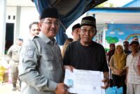 Bupati Tanjung Jabung Barat, Drs. H. Anwar Sadat, M.Ag., didampingi oleh Kepala Dinas Dukcapil, menyerahkan secara langsung bantuan dokumen kependudukan baru berupa Kartu Keluarga (KK) dan Kartu Tanda Penduduk (KTP) yang telah dicetak ulang kepada salah satu warga korban kebakaran di Kelurahan Teluk Nilau, Kecamatan Pengabuan. (FOTO : Dok. Prokopim TJB)