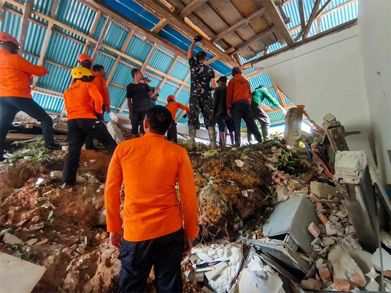 Sejumlah personel BASARNAS bersama tim gabungan dan warga setempat meninjau material longsor di Jalan Tanah Tumbuh, Kelurahan Empelu, Kecamatan Tanah Sepenggal, Kabupaten Bungo, Rabu (13/05). Satu unit alat berat ekskavator dikerahkan ke lokasi untuk mempercepat proses evakuasi dan pencarian korban yang tertimbun material tanah serta puing bangunan. (Foto: Dok. POS SAR Bungo)