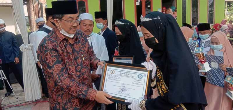 FOTO : Bupati Tanjab Barat, KH. Anwar Sadat dan Istri Hj. Fadhilah Saat Menyerahkan Piagam Kepada Wisudawan Santri Khotmil Qur'an.