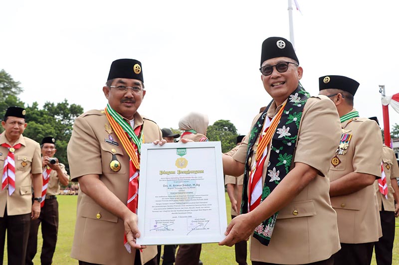 Bupati Tanjung Jabung Barat, H. Anwar Sadat Saat Menerima Piagam Penghargaan sebagai Tokoh Pramuka Perintis Utama dari Ketua Kwartir Nasional Gerakan Pramuka, Komjen Pol. (Purn.) Drs. Budi Waseso pada Apel Besar Peringatan Hari Pramuka ke-64 di Halaman Kantor Bupati Tanjung Jabung Timur, Rabu (19/11/25). FOTO : DOKPIM