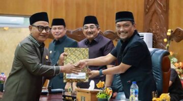 SINERGI EKSEKUTIF-LEGISLATIF: Bupati Tanjung Jabung Barat, Drs. H. Anwar Sadat, M.Ag. (kiri), menerima dokumen Pemandangan Umum Fraksi dari pimpinan DPRD dalam Rapat Paripurna LKPJ TA 2025 di Gedung DPRD Tanjab Barat, Senin (06/04). Sebanyak tujuh fraksi memberikan 