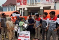 Bupati Solok, Jon Firman Pandu (tengah, topi hitam), didampingi perwakilan Pertamina Patra Niaga Regional Sumbagut, menyerahkan secara simbolis paket bantuan perlengkapan sekolah kepada perwakilan anak terdampak banjir bandang "Galodo" di Posko Batang Barus, Kabupaten Solok, Sumatera Barat, Oktober 2026. (FOTO : Dok. Pertamina)
