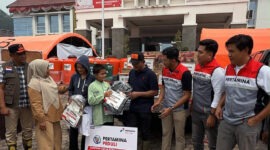Bupati Solok, Jon Firman Pandu (tengah, topi hitam), didampingi perwakilan Pertamina Patra Niaga Regional Sumbagut, menyerahkan secara simbolis paket bantuan perlengkapan sekolah kepada perwakilan anak terdampak banjir bandang "Galodo" di Posko Batang Barus, Kabupaten Solok, Sumatera Barat, Oktober 2026. (FOTO : Dok. Pertamina)