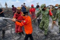 ubernur Jambi Al Haris (baju oranye) bersama Danrem 042/Gapu Brigjen TNI Nyamin (kanan, seragam TNI) bahu-membahu bersama tim Satgas gabungan menarik selang air di area bekas terbakar di Kabupaten Muaro Jambi. (FOTO : Dok. Istimewa)