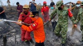 ubernur Jambi Al Haris (baju oranye) bersama Danrem 042/Gapu Brigjen TNI Nyamin (kanan, seragam TNI) bahu-membahu bersama tim Satgas gabungan menarik selang air di area bekas terbakar di Kabupaten Muaro Jambi. (FOTO : Dok. Istimewa)