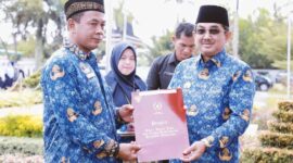 Bupati Tanjab Barat H. Anwar Sadat Saat Menyetahkan Satyalencana Karya Satya 30 tahun kepada Dartono (Kabag Sarpas Setda Tanjab Barat) pada upacara peringatan Hari KORPRI ke-51 tahun 2022 di halaman Kantor Bupati Tanjab Barat, Selasa (29/11/22). FOTO : Prokopim

