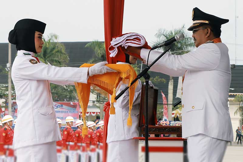 Bupati Tanjung Jabung Barat Drs H Anwar Sadat, M. Ag menyerahkan Duplikat Bendera Merah Putih untuk dikibarkan, Kamis (17/8/23). FOTO : FM
