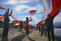 Ilustrasi Pemuda di Papua Bentangkan Bendera Merah Putih yang di Jahit Sendiri. FOTO : Ist/Net