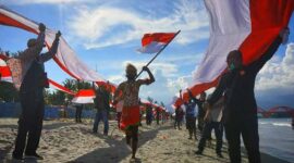 Ilustrasi Pemuda di Papua Bentangkan Bendera Merah Putih yang di Jahit Sendiri. FOTO : Ist/Net