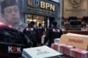 Petugas KPK membawa dokumen barang bukti dengan latar belakang para tahanan berompi oranye dan logo BPN. Operasi Tangkap Tangan (OTT) kakap di BPN Bogor. (FOTO : Dok. Ilustrasi/LT)