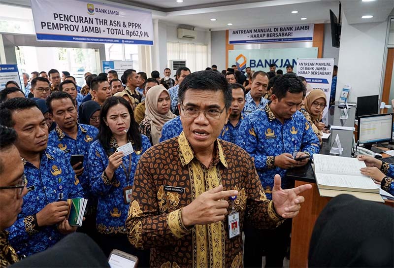 SAH ANTRE LAGI: Ekspresi sejumlah ASN saat mendengarkan pengumuman pencairan THR melalui Bank Jambi. Dengan sistem ATM dan mobile banking yang masih OFF, puluhan ribu pegawai terpaksa harus mengantre di loket fisik untuk mencairkan hak mereka. Kerumunan ini diprediksi akan terus membeludak hingga H-1 Lebaran seiring belum pulihnya sistem digital bank milik daerah tersebut. FOTO : Ilustrasi