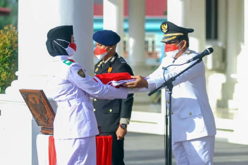 Bupati Tanjab Barat H. Anwar Sadat Menyerahkan Copy Bendera Mwrah Putih Kepada Paskibraka, Selasa (17/08/21). FOTO : PROKOPIM