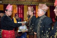 Gubernur Jambi H. Hasan Basri Agus (HBA) memberikan piagam dan surat keputusan LAM Jambi tentang Penganugerahan Gelar Adat Melayu kepada H Ridham Priskap (Sekda Provinsi Jambi) dengan gelar Penato Utamo Mulio. FOTO : Rosman M.