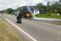 Personil Polres Muaro Jambi Semprot Jalan KM 13, 14 dan 17 Kec Mestong Kab. Muaro Jambi Pasca Banjir, Rabu (12/1/22). FOTO : HUMAS PMJ