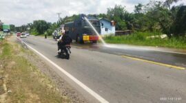 Personil Polres Muaro Jambi Semprot Jalan KM 13, 14 dan 17 Kec Mestong Kab. Muaro Jambi Pasca Banjir, Rabu (12/1/22). FOTO : HUMAS PMJ