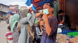 Ketua PWI Tanjab Barat Rita Anggraini memasangkan Masker ke Pedagang Jalan Nasional, Rabu (9/2/22). FOTO : ABAS