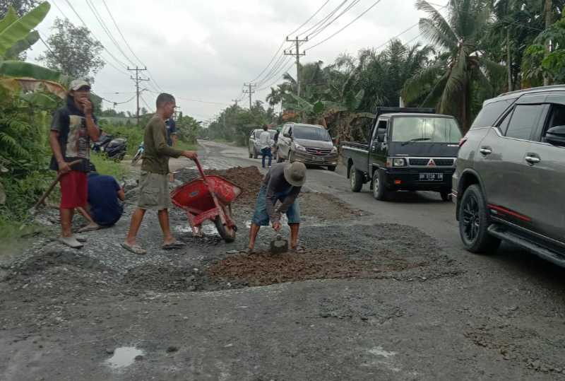 Warga RT 13 Kelurahan Bram Itam Kiri gotong royong memperbaiki titik Jalan Lintas Tungkal-Jambi yang Rusak. FOTO : By