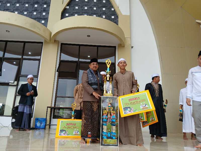 Bupati Tanjung Jabung Barat Drs H Anwar Sadat, M. Ag menyerahkan Piala Kepada Remaja Masjid Takzim Lorong Banten Juara 1 Festival Takbiran Idul Adha 1445 Hijriah. FOTO : LT