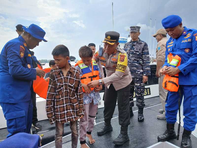 AKBP Agung Basuki, S. I. K., M. M dan Kasat Polair AKP Hermanto mengenakan Pelampung ke Anak Nelayan. FOTO : LT