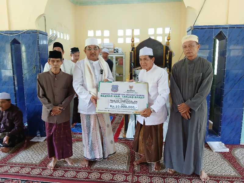 Bupati Tanjab Barat Drs H Anwar Sadat, M. Ag menyerahkan secara simbolis bantuan untuk Masjid Darussalam. FOTO : LT