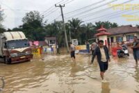 Petugas Polsek Merlung mengatur lalulintas kendaraan melintasi genangan Air Depan Mako Polsek Merlung (Dok Humas)