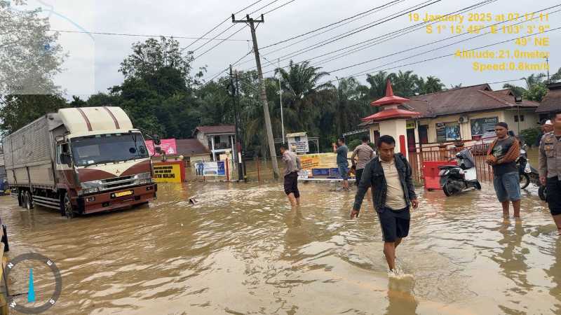 Petugas Polsek Merlung mengatur lalulintas kendaraan melintasi genangan Air Depan Mako Polsek Merlung (Dok Humas)