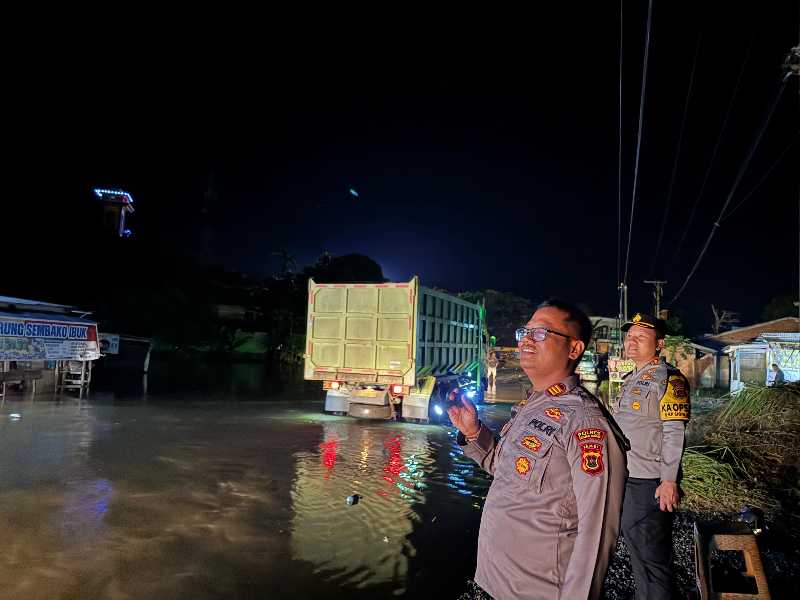 Kapolres Tanjab Barat AKBP Agung Basuki bersama Kapolsek Merlung AKP Agung Heru Wibowo beri isyarat kepada pengendara yang melintasi genangan Banjir (Humas)