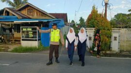 Seorang Personil Polres Tanjab Barat Bantu Pelajar Menyeberang Jalan (Ist)