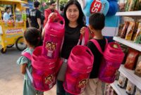 Seorang pengunjung menunjukkan tas ransel eksklusif Bright Gas berwarna pink setelah berbelanja di Booth Bright Store by Pertamina dalam pergelaran Jakarta Fair Kemayoran 2026. (FOTO : Dok. Pertamina)