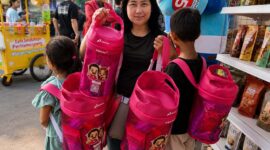 Seorang pengunjung menunjukkan tas ransel eksklusif Bright Gas berwarna pink setelah berbelanja di Booth Bright Store by Pertamina dalam pergelaran Jakarta Fair Kemayoran 2026. (FOTO : Dok. Pertamina)