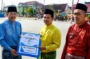 Bupati H. Anwar Sadat), menyerahkan piagam penghargaan dan dana pembinaan kepada Lurah Sungai Nibung Kecamatan Tungkal Ilir, Alfizan Fajri (tengah), sebagai Juara I Kelurahan Berprestasi Tingkat Kabupaten Tanjung Jabung Barat Tahun Anggaran 2026, Senin (10/08). (FOTO : Dok. Prokopim)