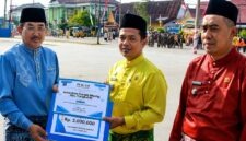 Bupati H. Anwar Sadat), menyerahkan piagam penghargaan dan dana pembinaan kepada Lurah Sungai Nibung Kecamatan Tungkal Ilir, Alfizan Fajri (tengah), sebagai Juara I Kelurahan Berprestasi Tingkat Kabupaten Tanjung Jabung Barat Tahun Anggaran 2026, Senin (10/08). (FOTO : Dok. Prokopim)