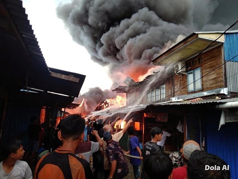 MEMBARA: Kobaran api disertai kepulan asap tebal menghanguskan puluhan bangunan di Pasar Teluk Nilau, Kecamatan Pengabuan, Tanjab Barat, Jumat (1/5). Sebanyak 70 KK dilaporkan terdampak akibat musibah ini. (FOTO : Humas Res TJB)