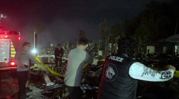 Petugas kepolisian memasang garis polisi di lokasi pascabencana kebakaran yang menghanguskan puluhan rumah warga di Kelurahan Teluk Nilau, Kecamatan Pengabuan, Jambi. Tim gabungan dan pemadam kebakaran masih berjaga di lokasi untuk memastikan titik api sepenuhnya padam. (FOTO : Dok. LINTASTUNGKAL.COM)