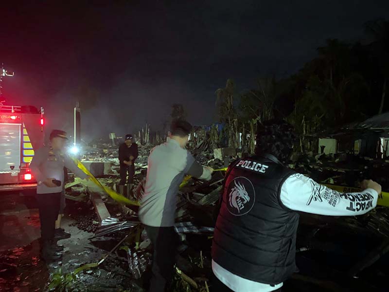 Petugas kepolisian memasang garis polisi di lokasi pascabencana kebakaran yang menghanguskan puluhan rumah warga di Kelurahan Teluk Nilau, Kecamatan Pengabuan, Jambi. Tim gabungan dan pemadam kebakaran masih berjaga di lokasi untuk memastikan titik api sepenuhnya padam. (FOTO : Dok. LINTASTUNGKAL.COM)