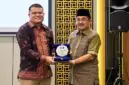 Bupati Tanjab Barat Anwar Sadat (kanan) memegang plakat bersama perwakilan manajemen BRI Cabang Kuala Tungkal dalam acara penandatanganan kerja sama pemanfaatan jasa dan layanan perbankan yang digelar di Aston Jambi, Jumat (25/9/2026).  (Foto: Dok. Humas)