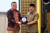 Bupati Tanjab Barat Anwar Sadat (kanan) memegang plakat bersama perwakilan manajemen BRI Cabang Kuala Tungkal dalam acara penandatanganan kerja sama pemanfaatan jasa dan layanan perbankan yang digelar di Aston Jambi, Jumat (25/9/2026).  (Foto: Dok. Humas)
