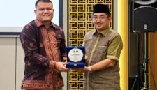 Bupati Tanjab Barat Anwar Sadat (kanan) memegang plakat bersama perwakilan manajemen BRI Cabang Kuala Tungkal dalam acara penandatanganan kerja sama pemanfaatan jasa dan layanan perbankan yang digelar di Aston Jambi, Jumat (25/9/2026).  (Foto: Dok. Humas)