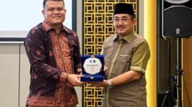 Bupati Tanjab Barat Anwar Sadat (kanan) memegang plakat bersama perwakilan manajemen BRI Cabang Kuala Tungkal dalam acara penandatanganan kerja sama pemanfaatan jasa dan layanan perbankan yang digelar di Aston Jambi, Jumat (25/9/2026).  (Foto: Dok. Humas)