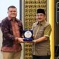 Bupati Tanjab Barat Anwar Sadat (kanan) memegang plakat bersama perwakilan manajemen BRI Cabang Kuala Tungkal dalam acara penandatanganan kerja sama pemanfaatan jasa dan layanan perbankan yang digelar di Aston Jambi, Jumat (25/9/2026).  (Foto: Dok. Humas)