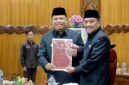 Wakil Bupati Dr. H. Katamso, SA, SE, ME (kiri), menyerahkan dokumen Nota Pengantar Rancangan Perubahan KUA-PPAS APBD Tahun Anggaran 2026 kepada Wakil Ketua DPRD Tanjab Barat, H. Muh. Syafril Simamora, SH (kanan), dalam Rapat Paripurna DPRD, Selasa (11/08). (Foto: Dok. Humas/Prokopim)