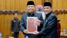 Wakil Bupati Dr. H. Katamso, SA, SE, ME (kiri), menyerahkan dokumen Nota Pengantar Rancangan Perubahan KUA-PPAS APBD Tahun Anggaran 2026 kepada Wakil Ketua DPRD Tanjab Barat, H. Muh. Syafril Simamora, SH (kanan), dalam Rapat Paripurna DPRD, Selasa (11/08). (Foto: Dok. Humas/Prokopim)
