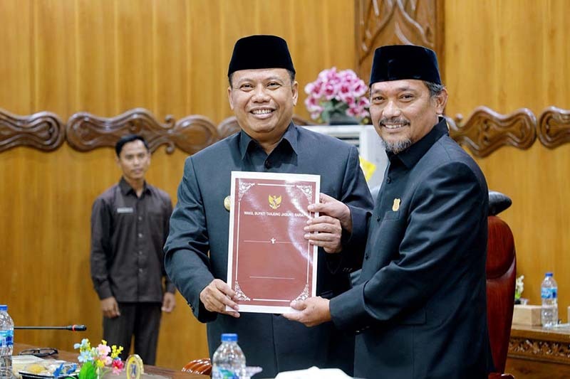Wakil Bupati Dr. H. Katamso, SA, SE, ME (kiri), menyerahkan dokumen Nota Pengantar Rancangan Perubahan KUA-PPAS APBD Tahun Anggaran 2026 kepada Wakil Ketua DPRD Tanjab Barat, H. Muh. Syafril Simamora, SH (kanan), dalam Rapat Paripurna DPRD, Selasa (11/08). (Foto: Dok. Humas/Prokopim)