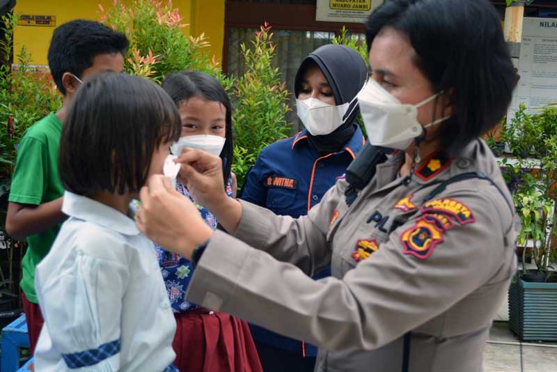 Kasat Binmas Polresta Jambi Kompol Mardonna Lamtio Memasang dan Membagikan Masker Saat Vaksinasi Siswa SDN 64 Kota Jambi, Kamis (10/2/22). FOTO : Humas PMJ.