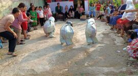 
Peserta Tengah Mengikuti Lomba Lari dalam Karung Pakai Helm di RT 18 Patunas, Minggu (13/8/23). FOTO : LT

