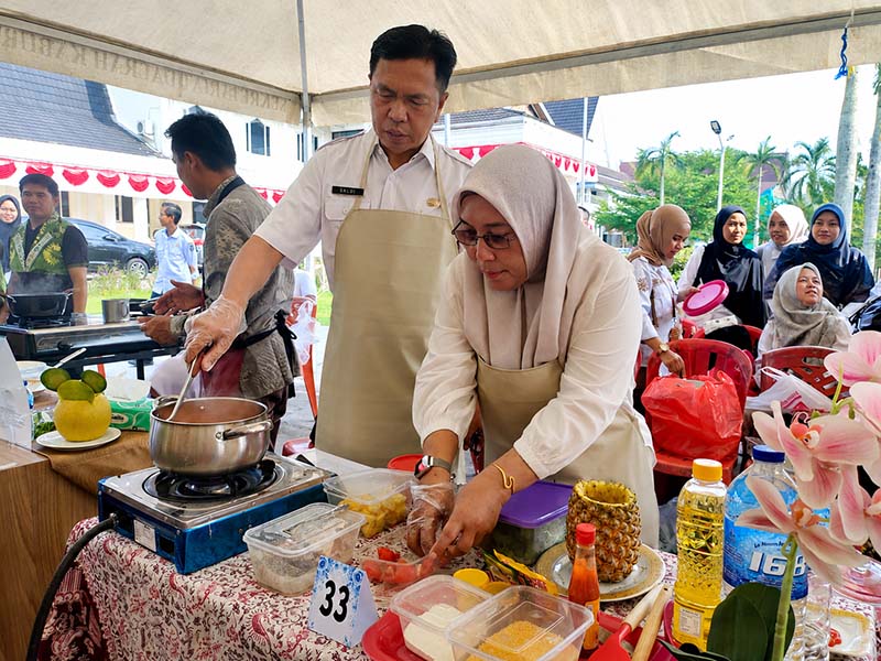Kepala BKPSDM Kabupaten Tanjung Jabung Barat, Saldi, S.H. (kiri) peserta (nomor meja 33) bersama staf sedang kompak mengolah menu masakan dalam Lomba Masak Serba Ikan (GEMARIKAN) yang digelar di halaman Kantor Bupati Tanjung Jabung Barat, Rabu (12/8/2026). (FOTO : Dok. BKPSDM TJB)