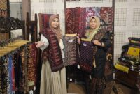 SINERGI PELESTARIAN BUDAYA: Ketua Persit KCK Cabang XXIII Kodim 0415/Jambi, Ny. Chichi Putra Negara (kiri), bersama Ny. Ruslaini Fadli (kanan) menunjukkan kain Batik Jambi motif unggulan di Booth 65 pameran 